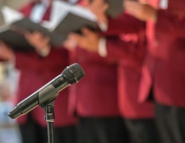 Microphone and mens choir Microphone on a stand in front of mens choir members holding singing book while performing in a cathedral in Rochester, Kent, UK